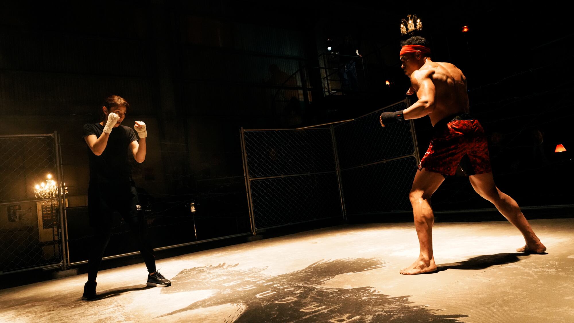 Two fighters circle each other in a dim warehouse ring