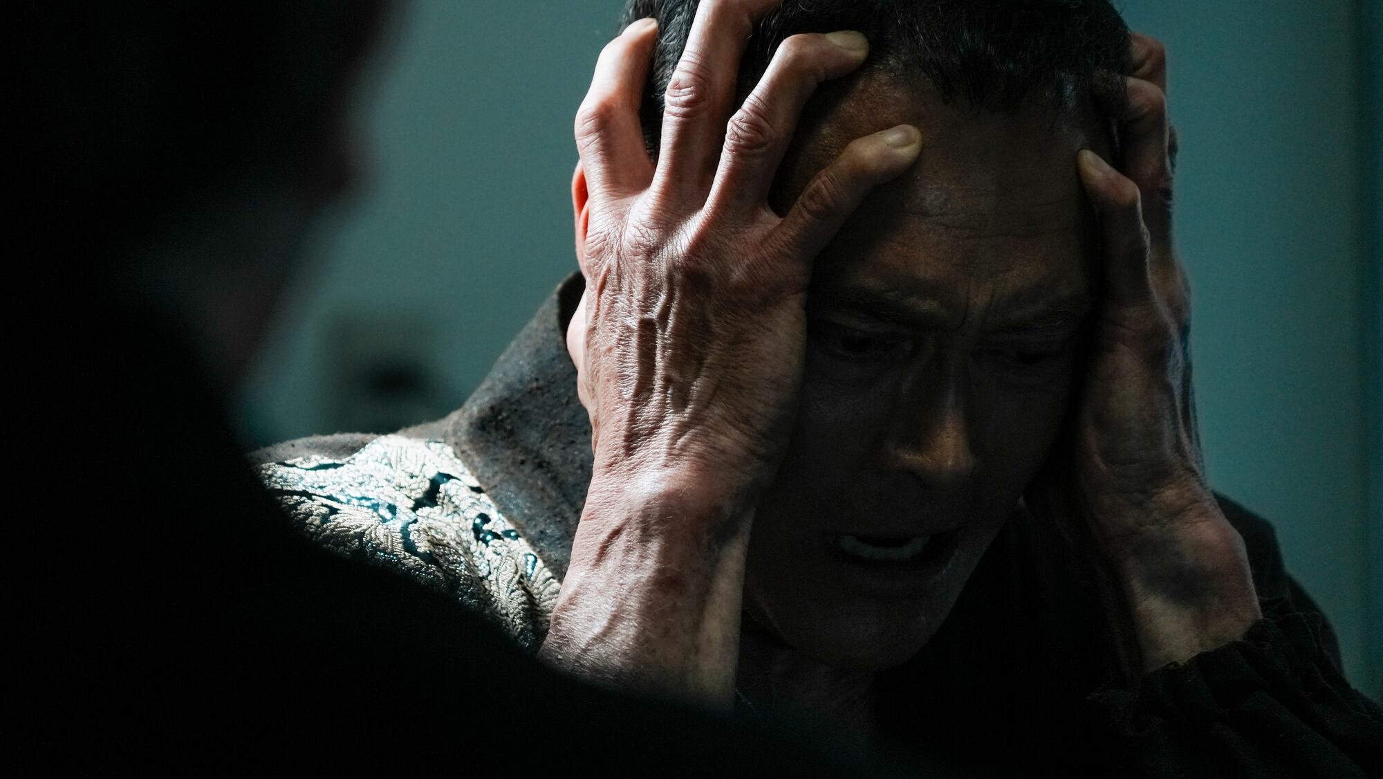 Mark Dacascos clutches his head in blue light