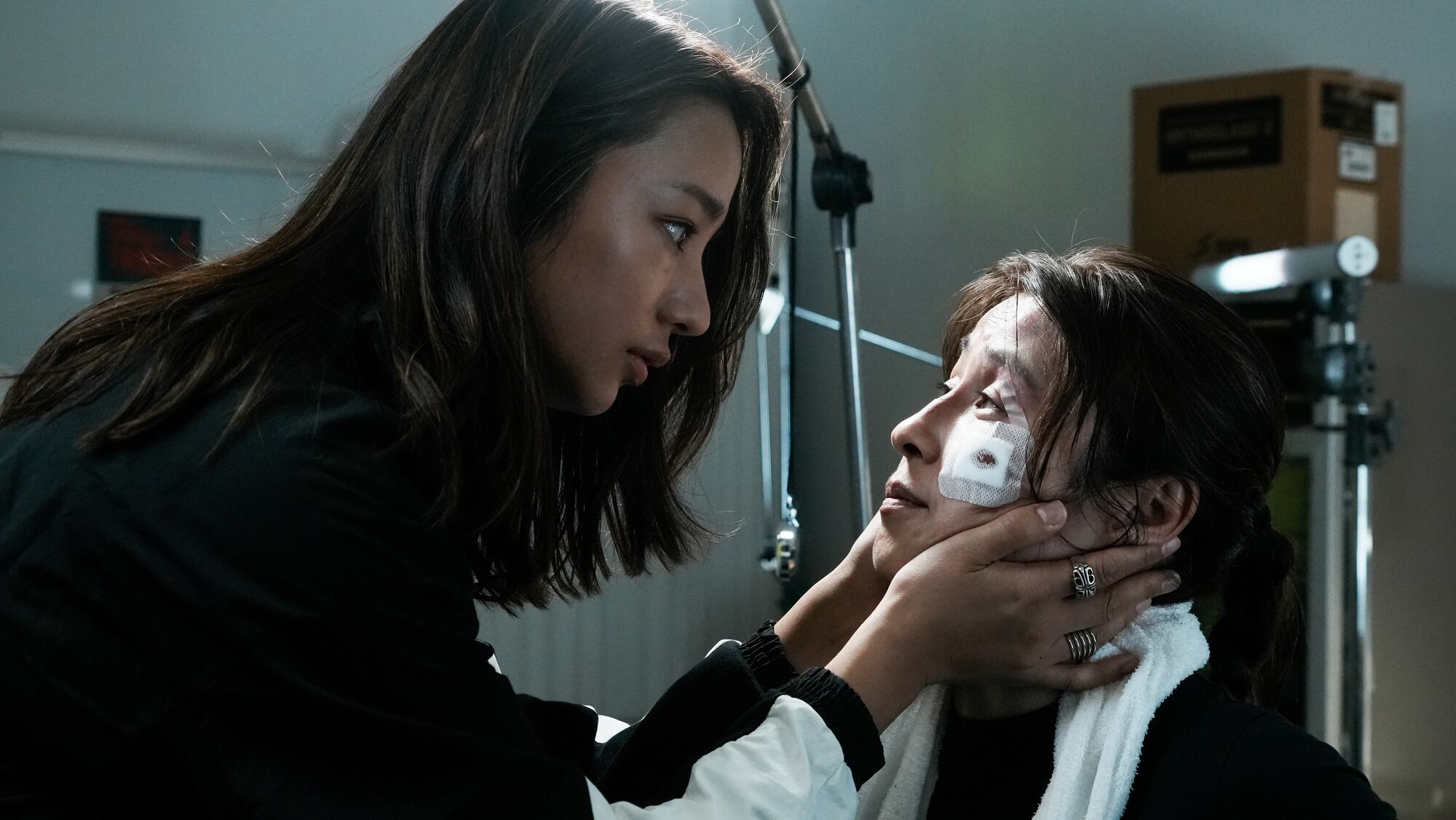 One woman steadies another whose cheek is bandaged